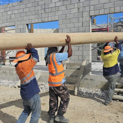 Construction workers carrying large structural timber beams during an active commercial construction project by Build N Concrete Ltd.