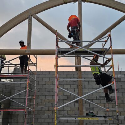 Construction workers installing large curved timber trusses and structural framing on a specialised commercial building project by Build N Concrete Ltd.