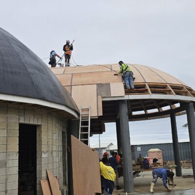 Workers installing curved roof cladding and structural timber framing on a specialised commercial construction project by Build N Concrete Ltd.