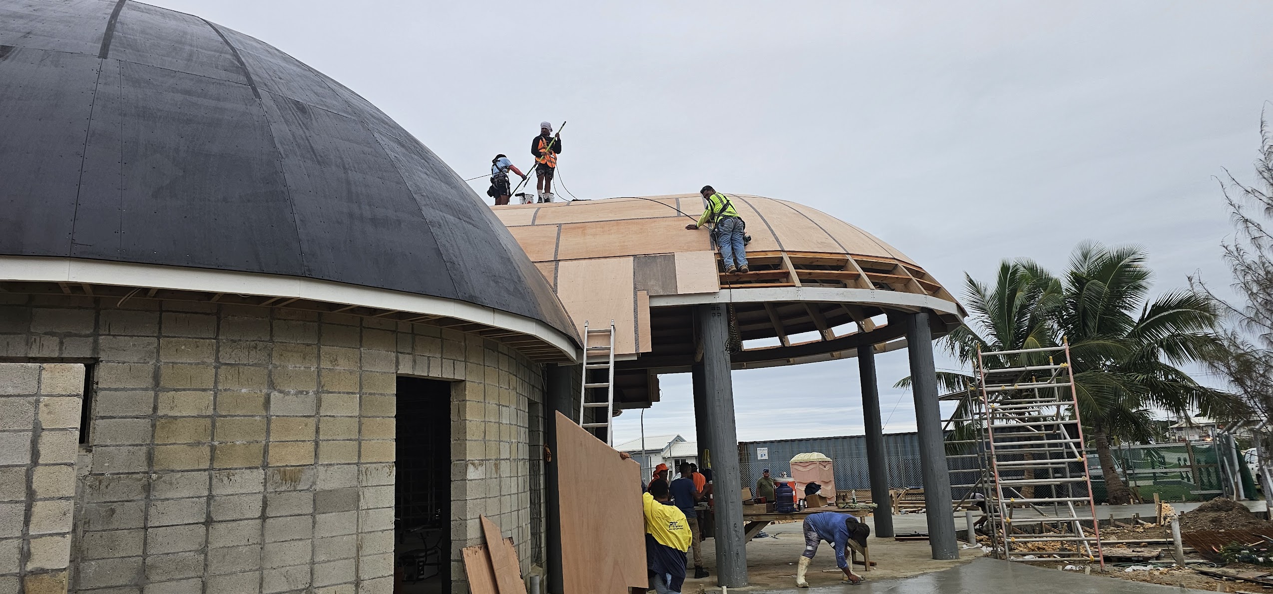 Workers installing curved roof cladding and structural timber framing on a specialised commercial construction project by Build N Concrete Ltd.